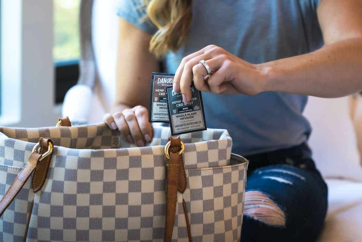 A woman places two single-serve Danodan CBD packets in her purse.
