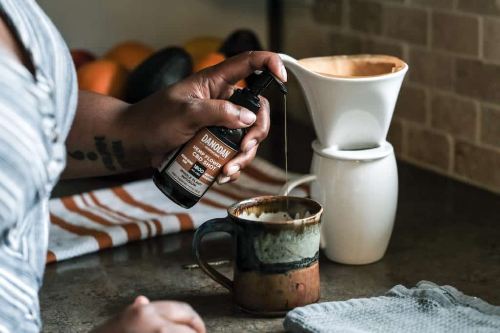 A woman dispenses Danodan CBD into a mug of coffee