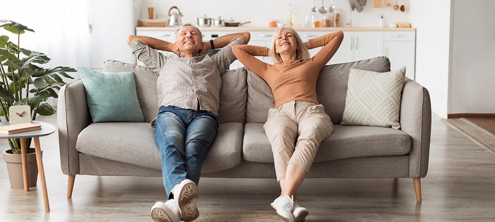 Elderly mature couple relaxed at home on their sofa after using organic CBD oil full spectrum for relief. 